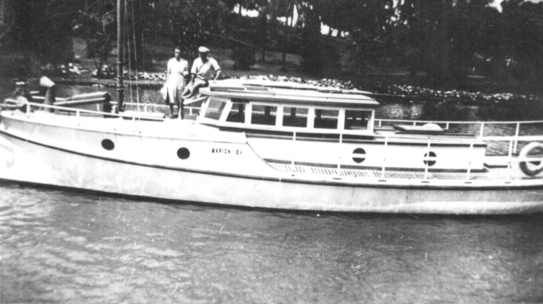 Black and white family photograph of the timber launch Marion with two family members aboard