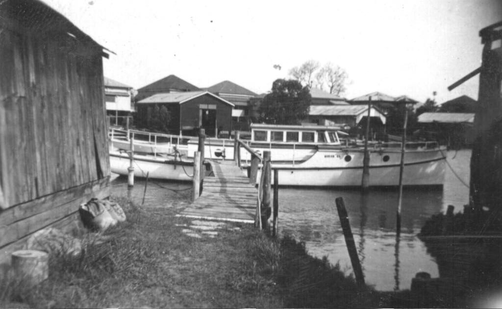 Black and white photograph of the old family boatshed and jetty with timber launches moored alongside